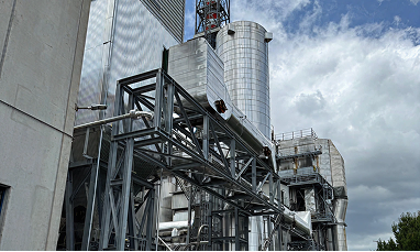 Operatore con casco di sicurezza e giacca ad alta visibilità regola una valvola su un impianto industriale di Acea Ambiente dotato di tubazioni e manometri 