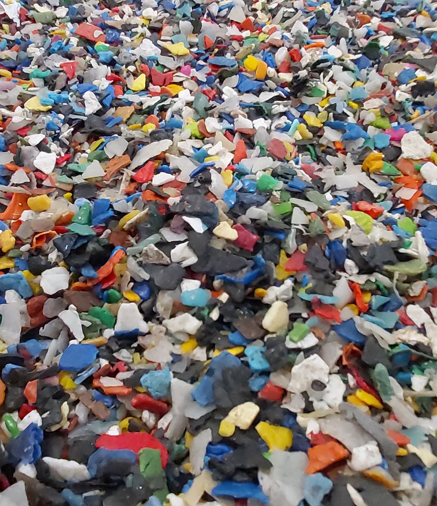 Mano che regge scaglie e granuli di plastica colorati