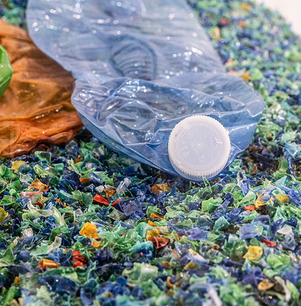 Bottiglie di plastica schiacciate su un letto di frammenti colorati di plastica riciclata